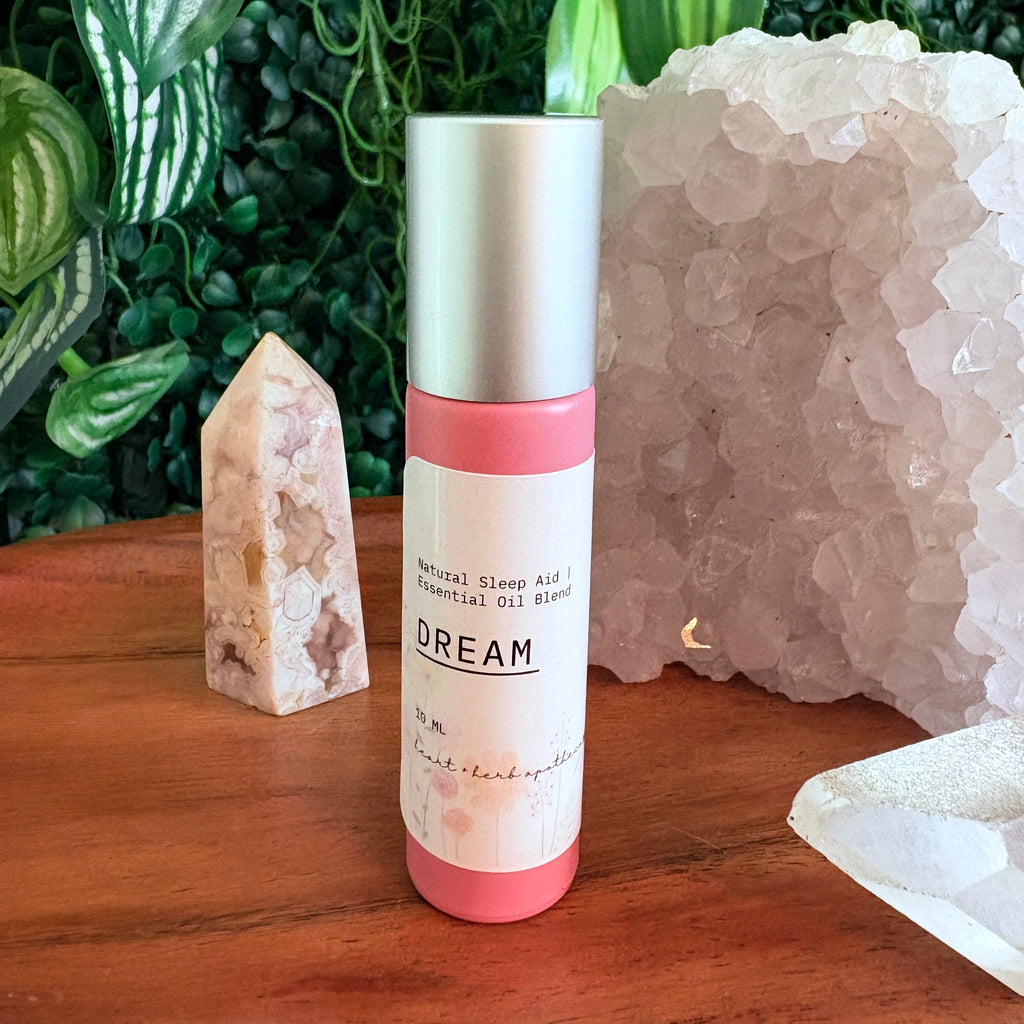 Roll-on bottle labeled 'Dream' on a wooden surface with crystals and plants in the background